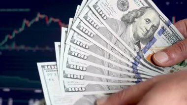 Bir adam borsa fiyat tablosunun önünde Amerikan dolarlarını sayıyor. Kârlı yatırımcı borsa ve finans sektörü
