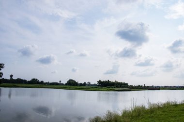 Orman göl ve dramatik gökyüzü ile çevrili.