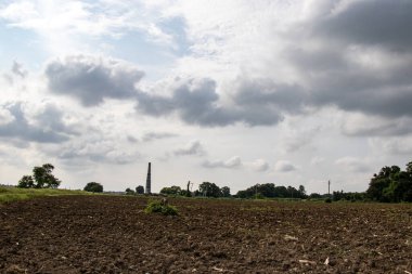Çiftçilik arazisi, dramatik gökyüzü, tuğla baca