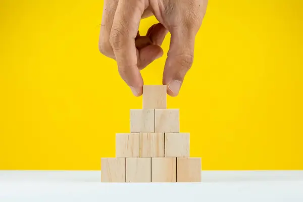 Hands of person stacking wooden blocks on table