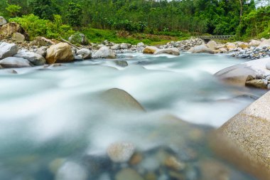 Güzel bir dağ nehir tropikal tepeler ve arka planda bir Kota Belud Sabah Malezya Borneo, Mount Kinabalu ile kayalar arasında akan doğal manzarası.