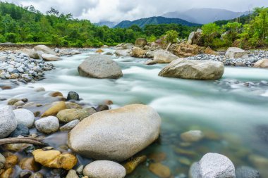 Güzel bir dağ nehir tropikal tepeler ve arka planda bir Kota Belud Sabah Malezya Borneo, Mount Kinabalu ile kayalar arasında akan doğal manzarası.