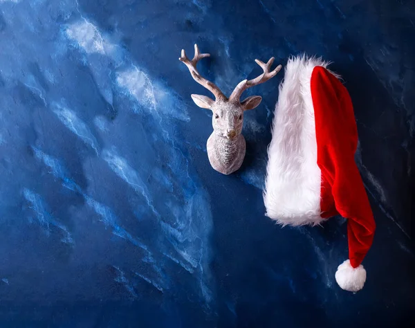 クリスマスの伝統的なシンボル 暗い青の雑音の背景にサンタクロースの帽子と鹿 テキスト用の場所 郵便はがき — ストック写真