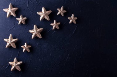 Parlak yeni yıl dekorasyonlarıyla dolu bir arka plan. Siyah desenli duvarda dekoratif altın yıldızlar. Durgun hayat. Noel konsepti. Mesaj için yer. Kış tatili kartpostalı.