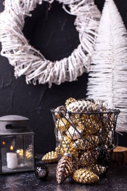 Yeni yıl süslemeleri. Dekoratif cam külahlı metal kova ve siyah desenli arka planda beyaz el yapımı çelenk. İskandinav minimalist tarzı. Durgun hayat