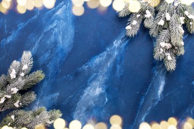 Derin mavi mırıldanma arkaplanındaki kürk ağacının ve bokeh ışıklarının çerçevesi. Basit bir Noel kompozisyonu. Üst Manzara. Metin için yer.