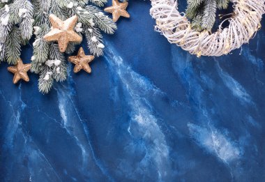 Dallardaki kürk ağacı, beyaz çelenk ve derin mavi mırıldanma arkaplanındaki şenlikli altın yıldızlar çerçevesi. Basit bir Noel kompozisyonu. Üst Manzara. Metin için yer.
