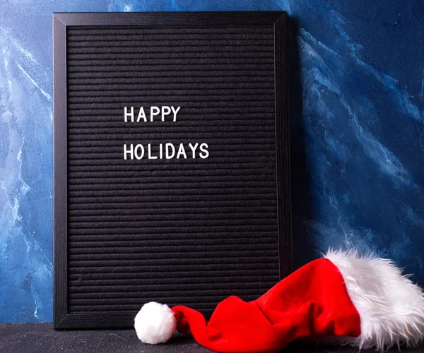 背景与新年或圣诞装饰 黑色的圣诞老公公的红帽子和深蓝色的墙壁相映成趣 安静的生活 圣诞节的概念冬季假期明信片 — 图库照片