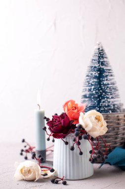 Şenlikli kış kartpostalı. Taze güller, yabani böğürtlenler ve dokulu duvarlara karşı mavi dekoratif ağaçlar. Durgun hayat. Noel konsepti. 