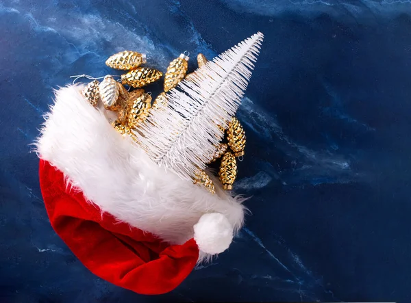 圣诞装饰品圣诞老人的红帽子和装饰树 在深蓝色的杂音背景上呈圆锥状 安静的生活 圣诞节的概念文字的位置 冬季假期明信片 — 图库照片