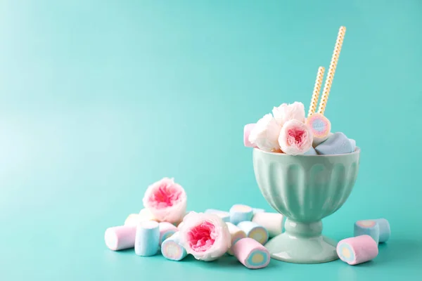 Romantic roses and sweets. Yummy marshmallows,  paper straws and tender pink roses in bowl on turquoise pastel background. Place for text. Postcard for birthday, Valentine day.