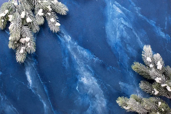 Frame from branches fur tree on deep blue murmur background. Simple Christmas composition. Top view. Place for  text.