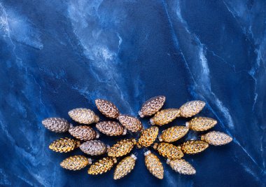 Parlak Noel süslemeleri ile düz bir sınır çizdi. Gri desenli arka planda cam altın, siyah, gümüş renkli dekoratif koniler. Durgun hayat. Üst Manzara. Kış tatili kartpostalı.