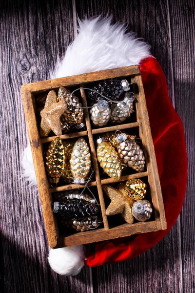 明るいクリスマスの装飾が施されたフラットレイアウト ヴィンテージ木製の背景にガラス金 銀装飾コーンと赤サンタス帽子とヴィンテージ木製の箱 まだ生きてる 最上階だ 冬休みはがき — ストック写真