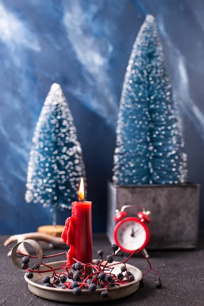 圣诞装饰品红色燃烧的蜡烛 在野蓝浆果 红色时钟和蓝色装饰树的乡村持有人与蓝色纹理背景 斯堪的纳维亚简约主义风格 静谧的生活 — 图库照片
