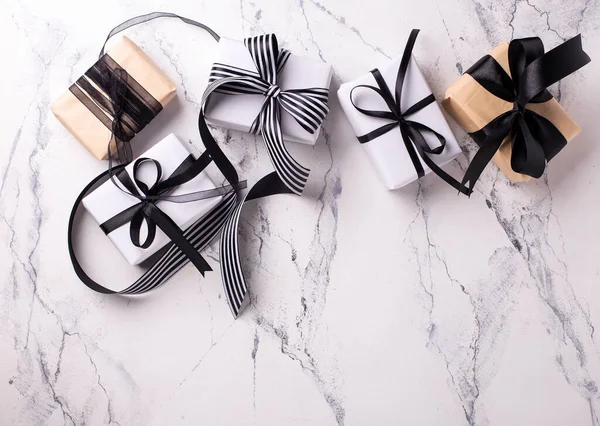 Boxes with wrapped  gifts  in black and white colors on white marble background. Top view. Place for text.