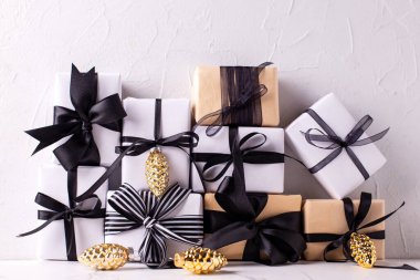 Beyaz desenli arka planda hediyeler ve altın renkli dekoratif koniler içeren paketlerin toplanması. İskandinav tarzı. Metin için yer.