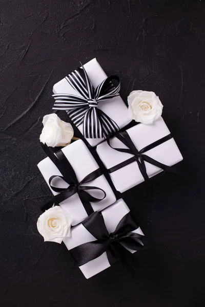 Négy Ajándék Csomagolt Dobozokban Fehér Rózsa Virágok Fekete Textúrájú Háttérrel — Stock Fotó
