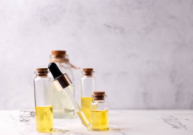 Açık gri desenli arka planda gerekli aroma yağına sahip şişeler ve damlalar. Seçici odaklanma. Metin için yer.