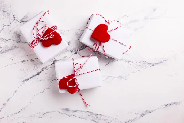 Wrapped white boxes with presents and hearts on white marble background. Top view.  Place for text. Postcard.