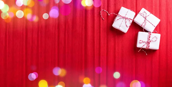 赤い質感の紙の背景にプレゼントとボケのライトの3つのラップボックスを持つバナー テキスト用の場所 トップ表示 — ストック写真