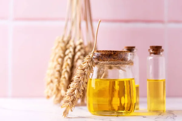 stock image Bottles with organic wheat germ oil against pink tiled wall.  Natural skin care products. Beauty blogging, salon treatment concept. Selective focus. Place for text.