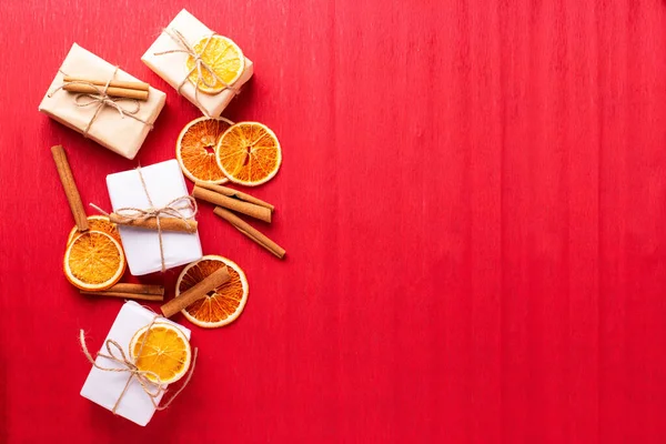 Opakowane Pudełka Prezentami Ozdobione Cynamonem Plastry Suszonych Pomarańczy Czerwonym Teksturowanym — Zdjęcie stockowe