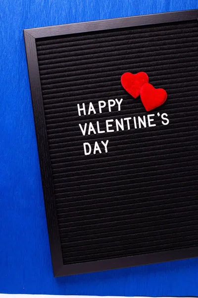 聖バレンタインデーの絵葉書 お祝いのフレーズと2つの赤い心をオ明るい青の紙のテクスチャの背景を持つレターボード 最上階だ ぼくえ光 ロイヤリティフリーのストック写真