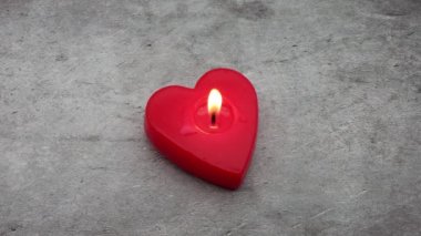 Kırmızı kalp şeklinde mum ve mum ışığı arka planda 4K izole edilmiş. Romantik Sevgililer Günü akşamı konsepti.