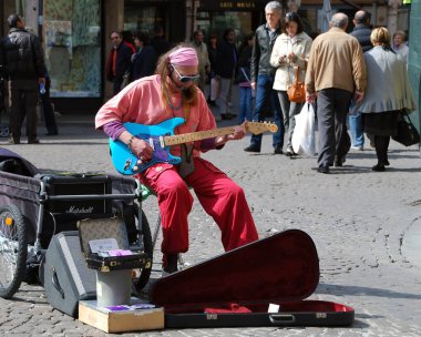 Mantua - Italy - March 27, 2010: Street performer playing rock music with an electric guitar in the historic downtown district of Mantova. Busking on street concept.