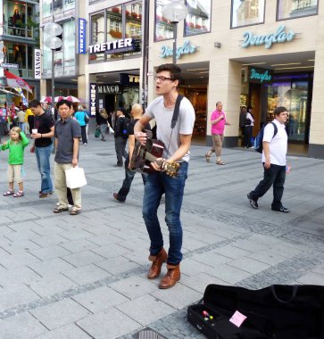 Munich - Germany: August 8, 2012: Street performer playing acoustic music with guitar in the historic downtown district of Munich. Busking on street concept.