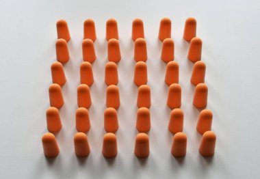 Beyaz arkaplanda turuncu köpük kulak tıkaçları izole edildi