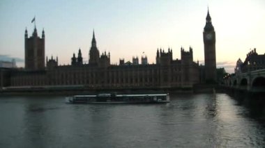 Londra 'daki Westminster Sarayı yakınlarındaki Thames nehrinin altından turistlerle dolu bir tekne geçiyor..