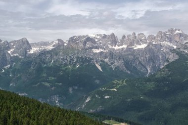 Fai della Paganella dağlarının manzarası bulutlu bir gökyüzünün altında yükselir. Brenta Dolomitleri, Trentino, İtalya.