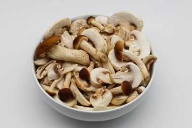 Çeşitli taze kesilmiş mantarlarla dolu beyaz bir kase..