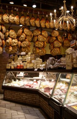 Bologna - İtalya - 27 Aralık 2024: İtalyan şarküteri sallanan prosciutto ve çeşitli peynirler sergileniyor.