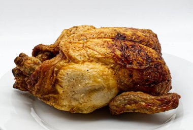 Lezzetli altın kavrulmuş tavuk. Beyaz bir tabakta. Aile yemeği için oyulmaya hazır.