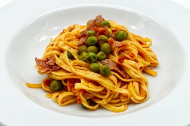 Bir tabak lezzetli İtalyan tagliatelle makarnası taze bezelye ve domates sosunda pişirilmiş jambon.