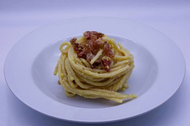 Kızarmış domuz pastırmalı ve pecorino romano peynirli, biberli, beyaz bir tabakta servis edilen geleneksel İtalyan usulü kremalı makarna..