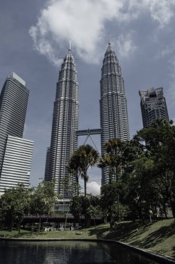 The famous twin towers of Kuala Lumpur emerging behind the vegetation in Malaysia clipart