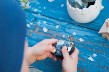 Mutlu Paskalyalar. Çocuklar ellerini mavi ahşap arka planda paskalya yumurtasını temizler..