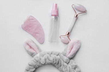 Patenli mermer yüz masajcıları ve kozmetik şişeleri, beyaz arka planda aksesuarlar..