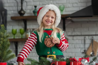 Noel şapkalı kız evde kurabiye ve kakao yiyor..