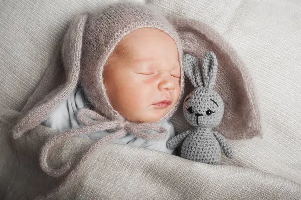 Newborn 3 weeks sleeping with rabbit toy close up. Baby care, colic, teething, healthy sleep.