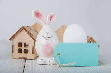 Mutlu Paskalya tebrik kartları. Minyatür ahşap ev. Tavşanlar, renkli yumurtalar, metin için etiketli bahar çiçekleri.