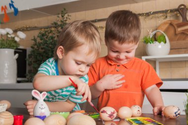Çocuklar Paskalya yumurtası boyuyor. Paskalya gelenekleri, yeni yürüyenlerle eğlence.