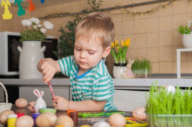 Toddler boy painting Easter egg close-up. Easter traditions and entertainment with children at home.