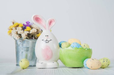 Mutlu Paskalya tebrik kartları. Minyatür ahşap ev. Tavşanlar, renkli yumurtalar, metin için etiketli bahar çiçekleri.