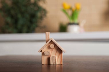 Minyatür ahşap bir ev modeli iç taraftaki bir masanın üstünde.