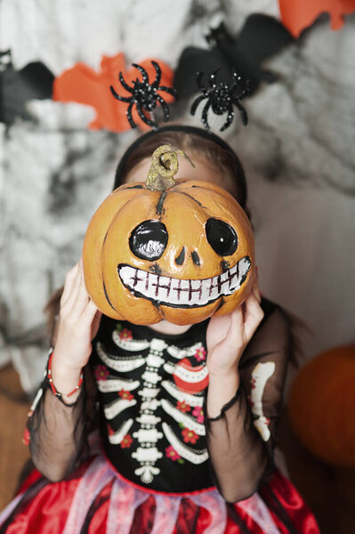 Girl with pumpkin fooling around at home on Halloween.